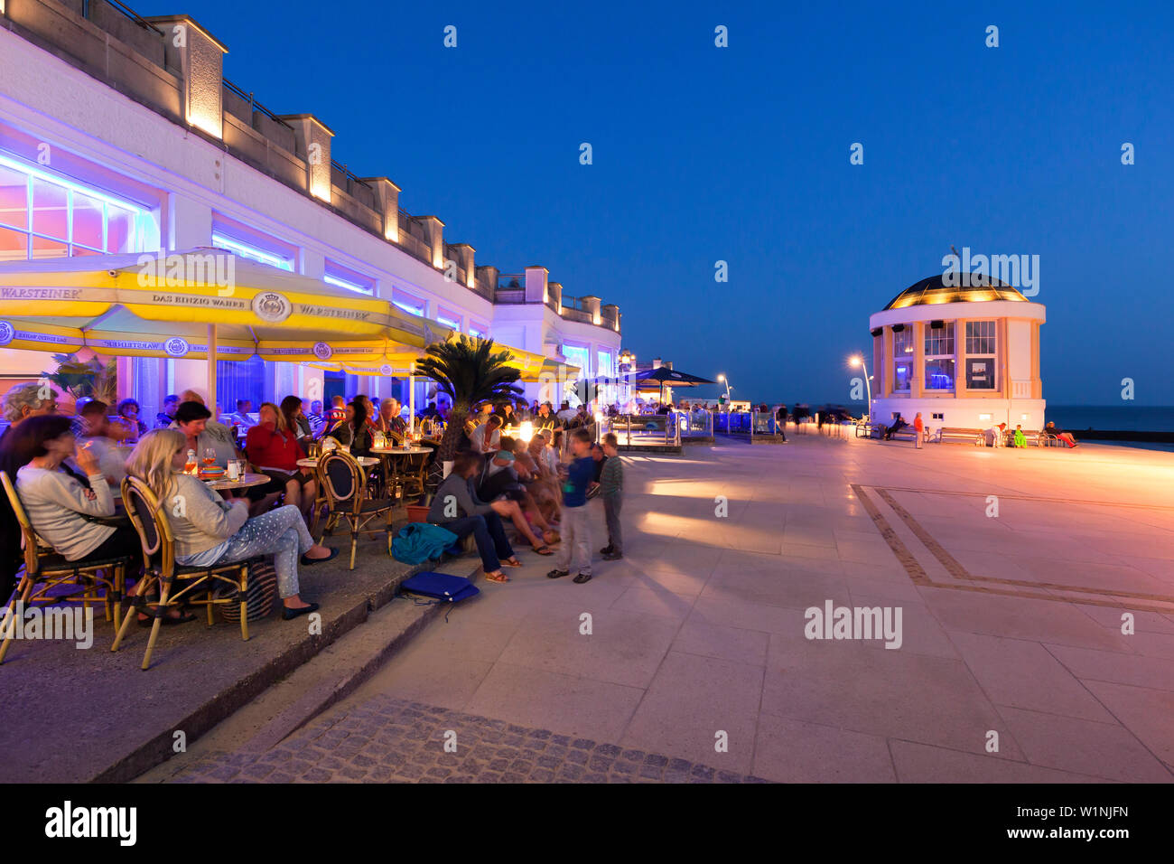 People sitting in a cafe on the beach promenade, Pavilion in the background, Borkum, Ostfriesland, Lower Saxony, Germany Stock Photo