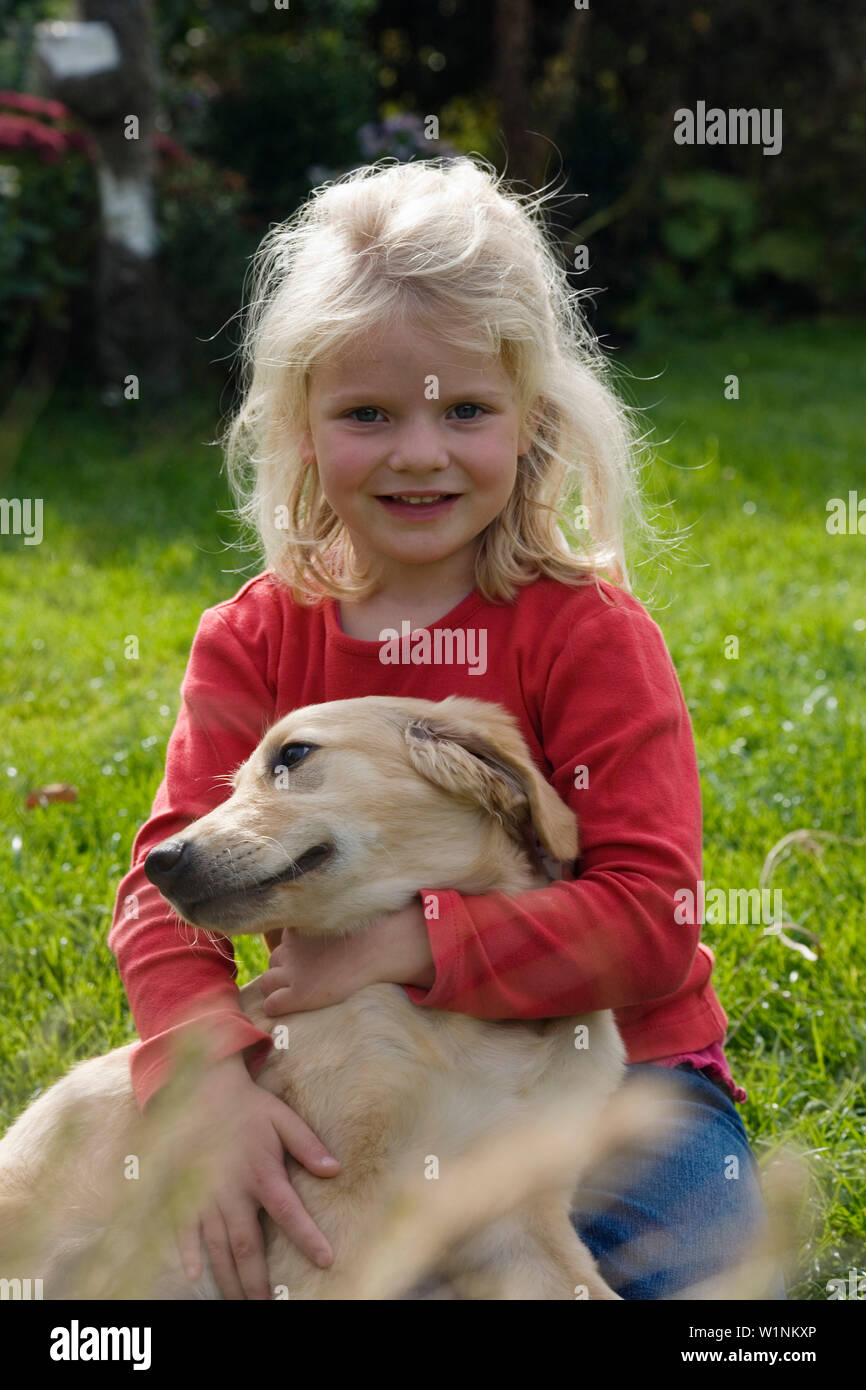 blond girl sitting in garden with dog Golden Retriever Stock Photo - Alamy
