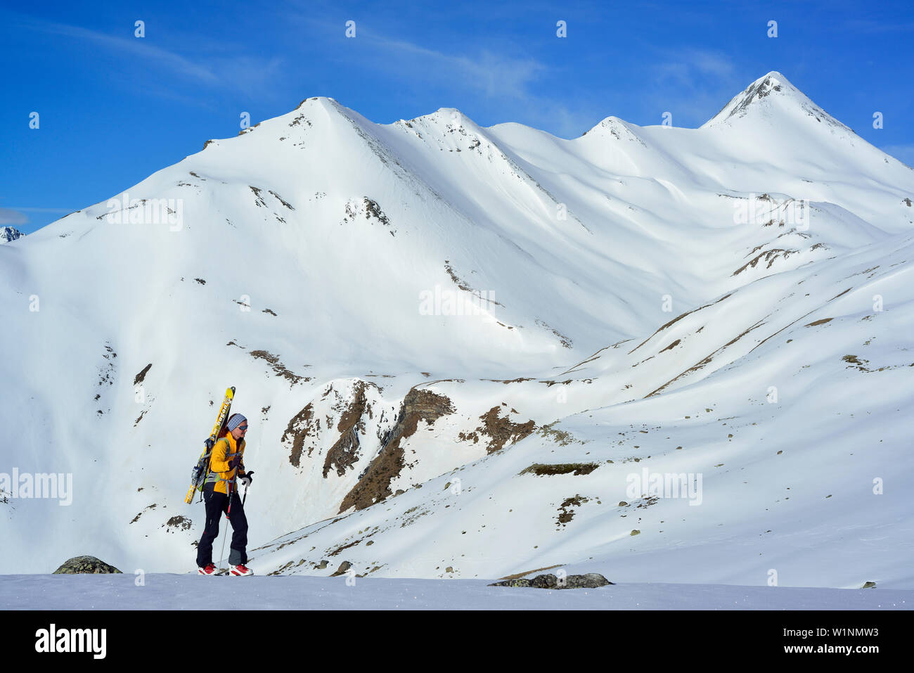 Female back-country skier ascending to Piz Kesch, Piz Blaisun in background, Engadin, Canton of Graubuenden, Switzerland Stock Photo