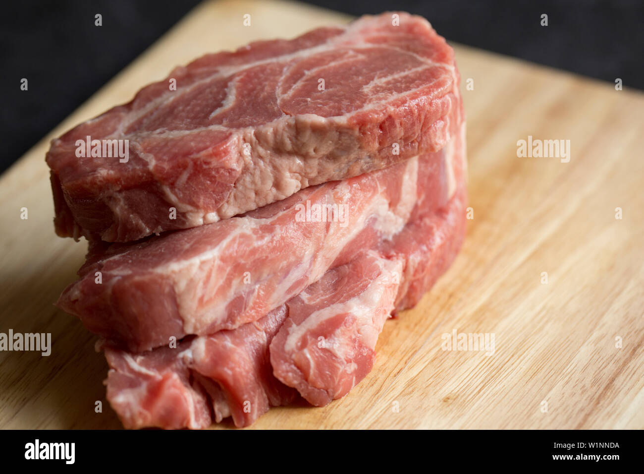 Three raw, uncooked British pork shoulder steaks bought from a supermarket in the UK. Dorset England UK GB Stock Photo