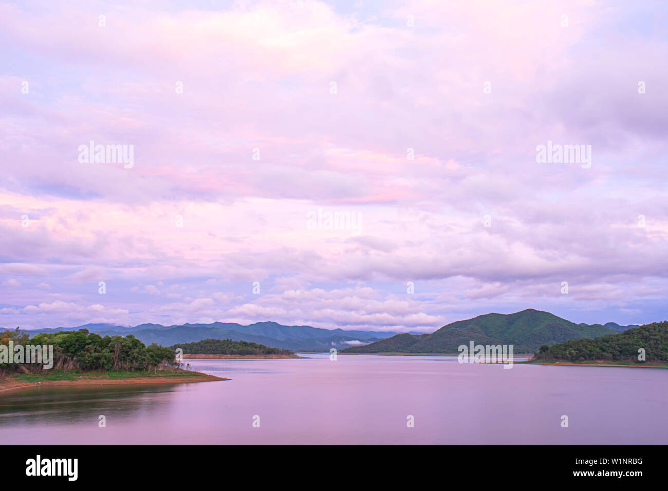 The reflection of the Sun and the clouds on the sky Background mountain and water at Kaeng Krachan dam in phetchaburi , Thailand. Stock Photo