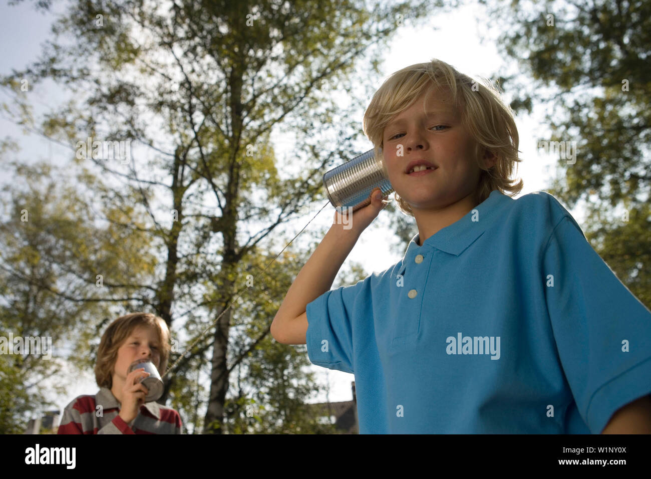 Two boys playing with a tin can phone, children's birthday party Stock Photo