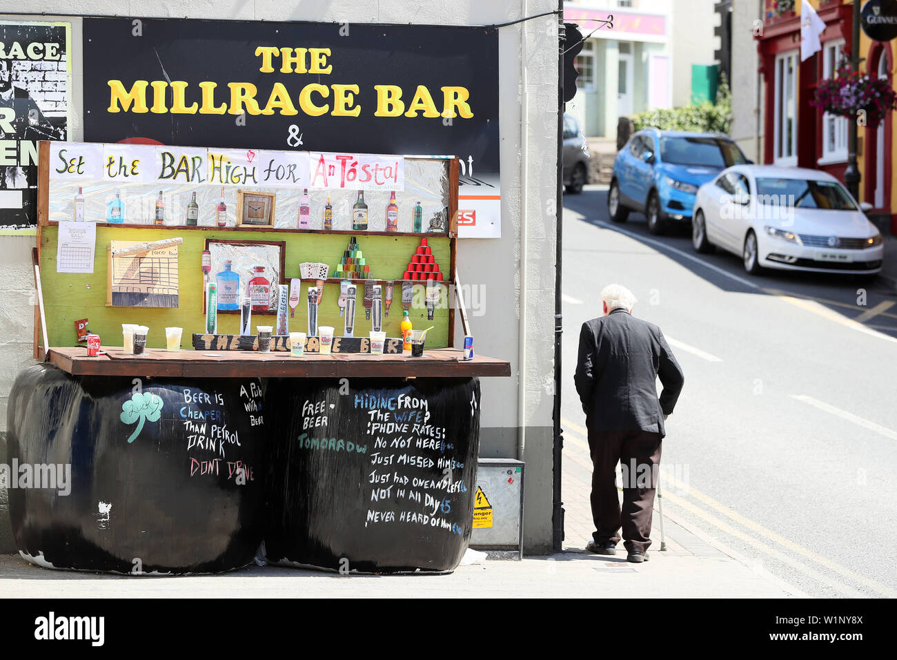 A man walks past a display titled 'Set the Bar High' outside the Millrace Bar, as residents of Drumshanbo, Co. Leitrim, are competing in the 'Stylish Silage' competition as part of the annual An Tostal festival. The competition consists of entries on various themes all of which have bales of silage as their main component. Stock Photo