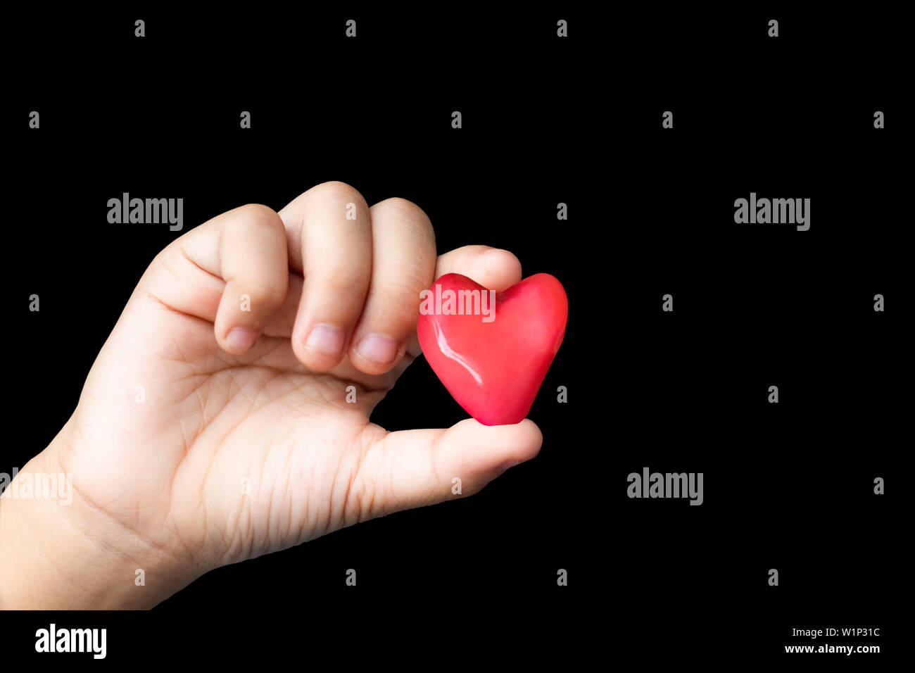 Isolated Hand holding a red candy shape heart on a black