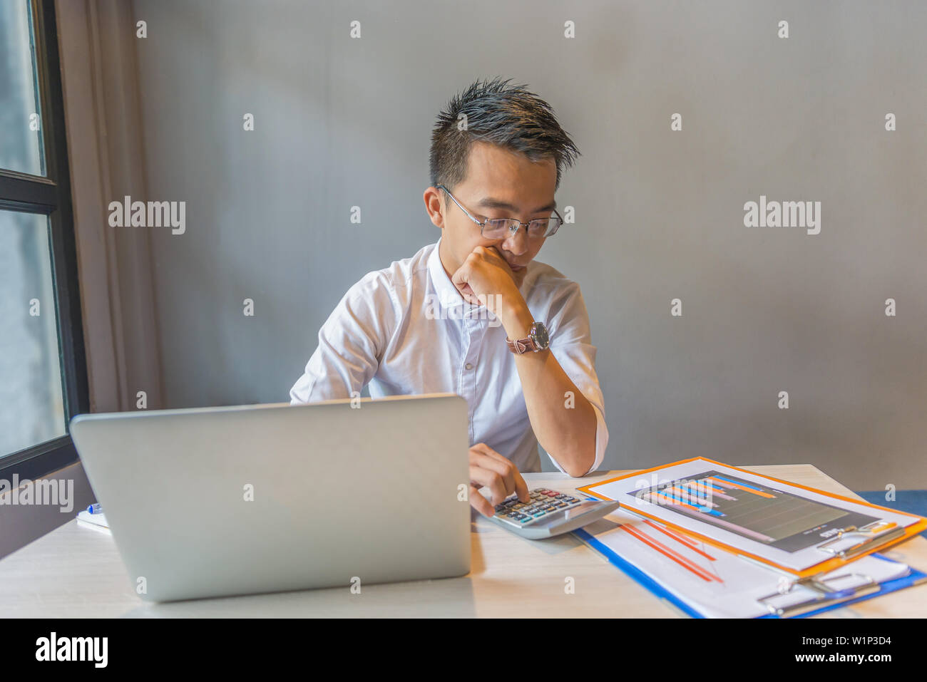 Wearing glasses financial accountant using calculator, analyzing graph document Stock Photo