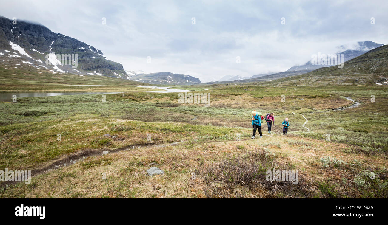 Two girls and a woman hiking on the Kungsleden Trek. Between Saltoluokta fjällstation and the hut Sitojaurestugorna, Laponia, Lapland, Sweden. Stock Photo