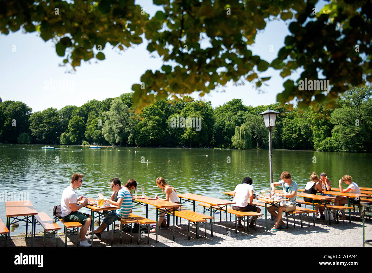 In the beer garden at the Seehaus in the English Garden in Munich, Bavaria, patrons are seated right at the lake Stock Photo