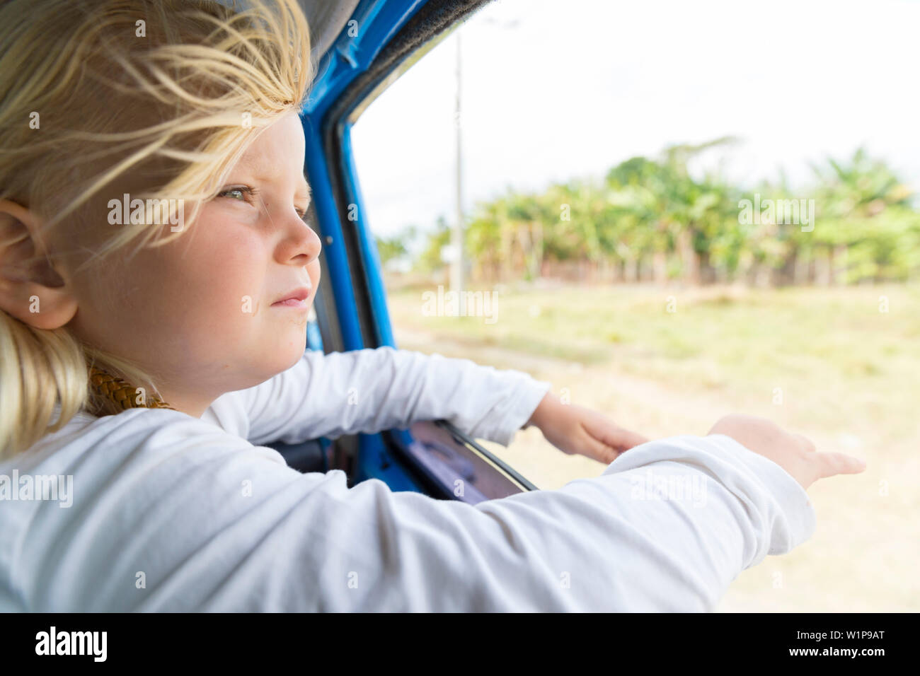 girl looking out of the window, hair blowing in the wind, on the way from Cayo Coco to Santa Clara, on the road, empty street, no traffic, horse-drawn Stock Photo