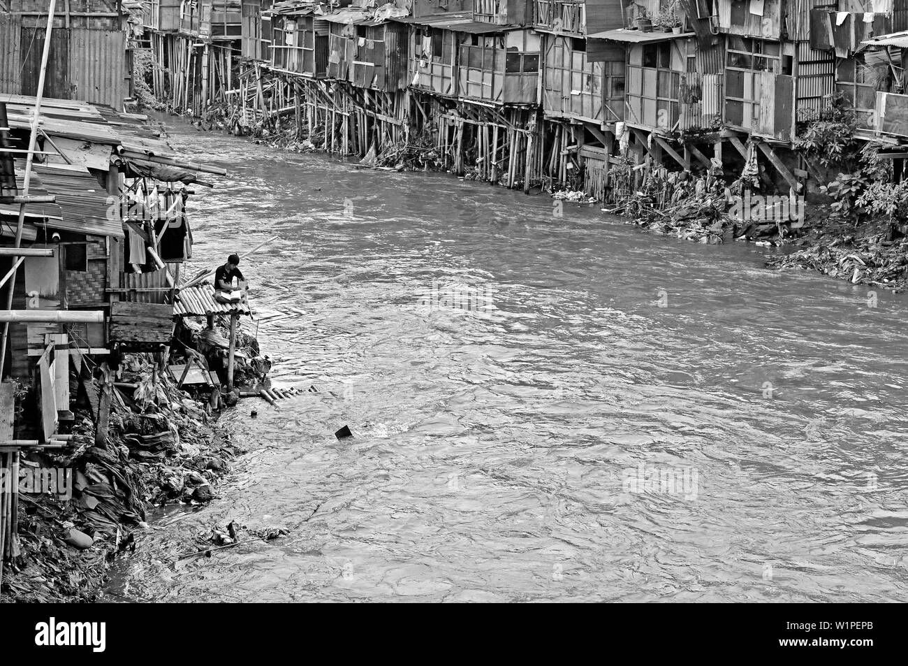 jakarta, indonesia - 2009.11.16: kampung melayu squatter living quarter at the banks of ciliwung river, young boy studying Stock Photo