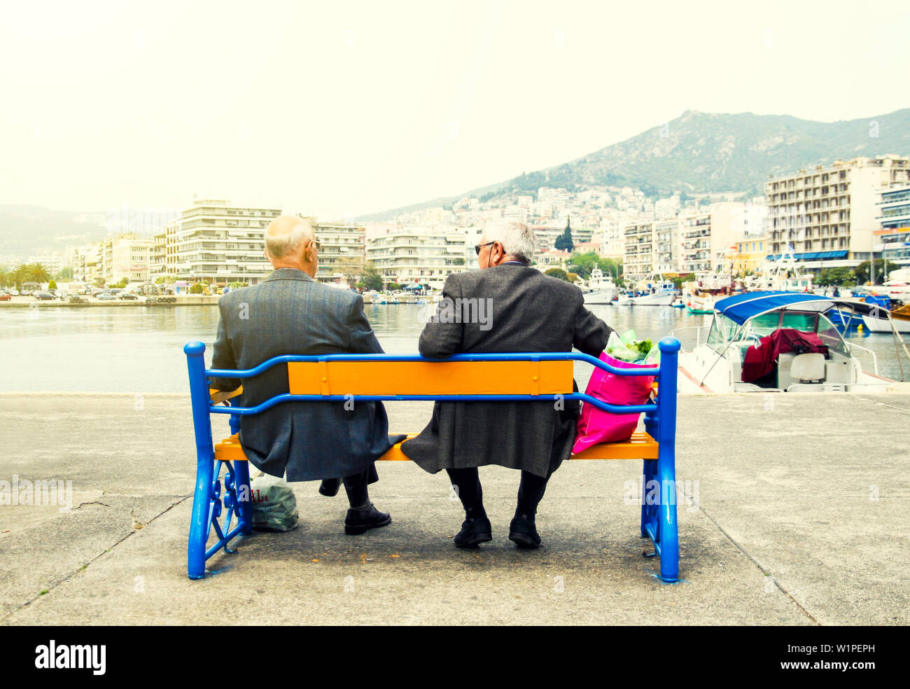 Two senior men sitting on a bench and watching the sea view Stock Photo