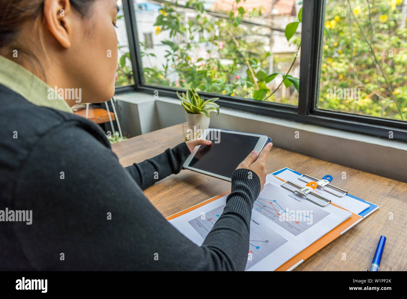 Woman using digital tablet at workplace next to window Stock Photo