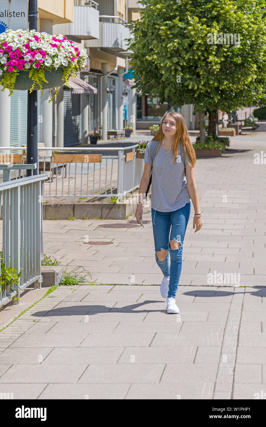 Pretty female teenager walking down the street in town centre looking away into the distance Stock Photo
