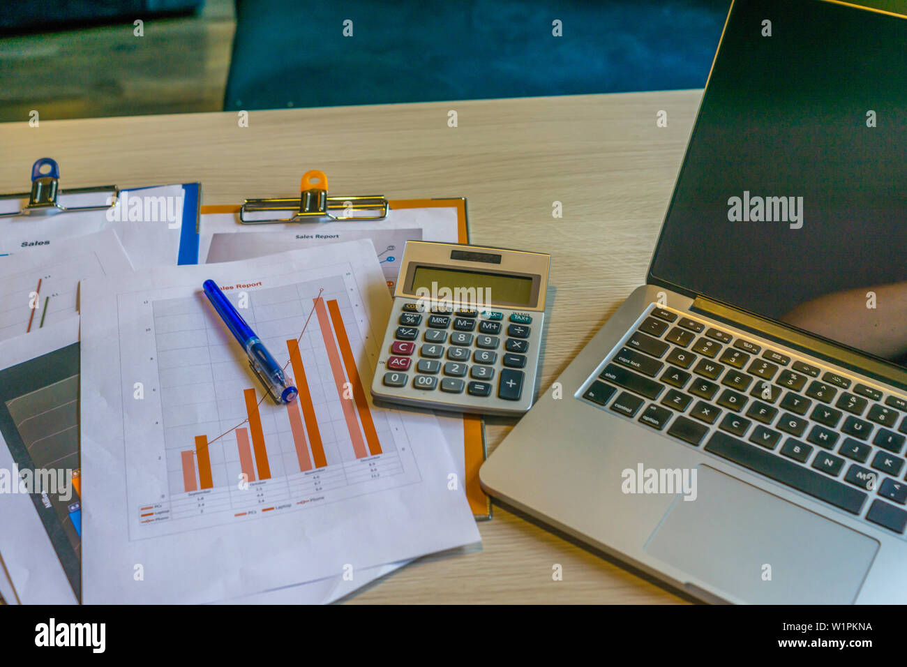 Close up of laptop graph documents on office desk Stock Photo