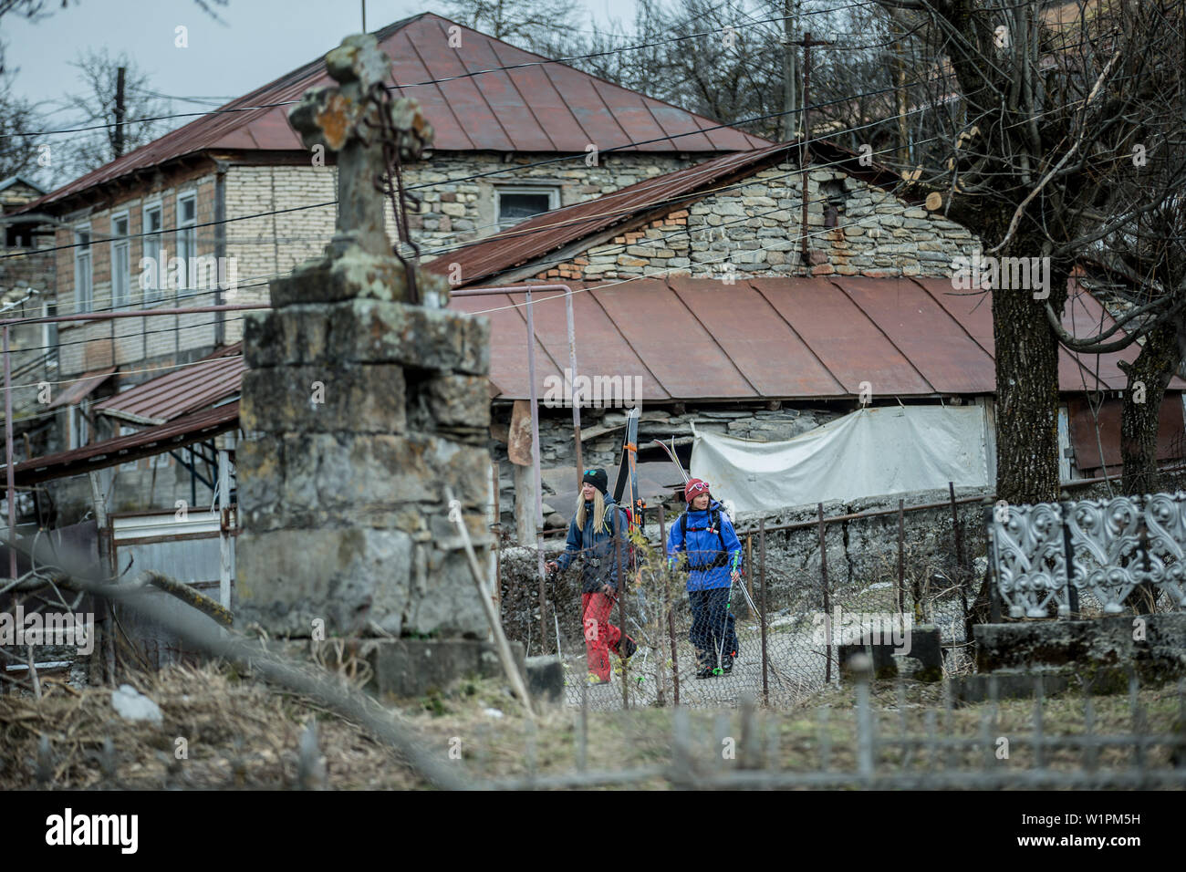 Two young female skiers wakling through a village, Gudauri, Mtskheta-Mtianeti, Georgia Stock Photo