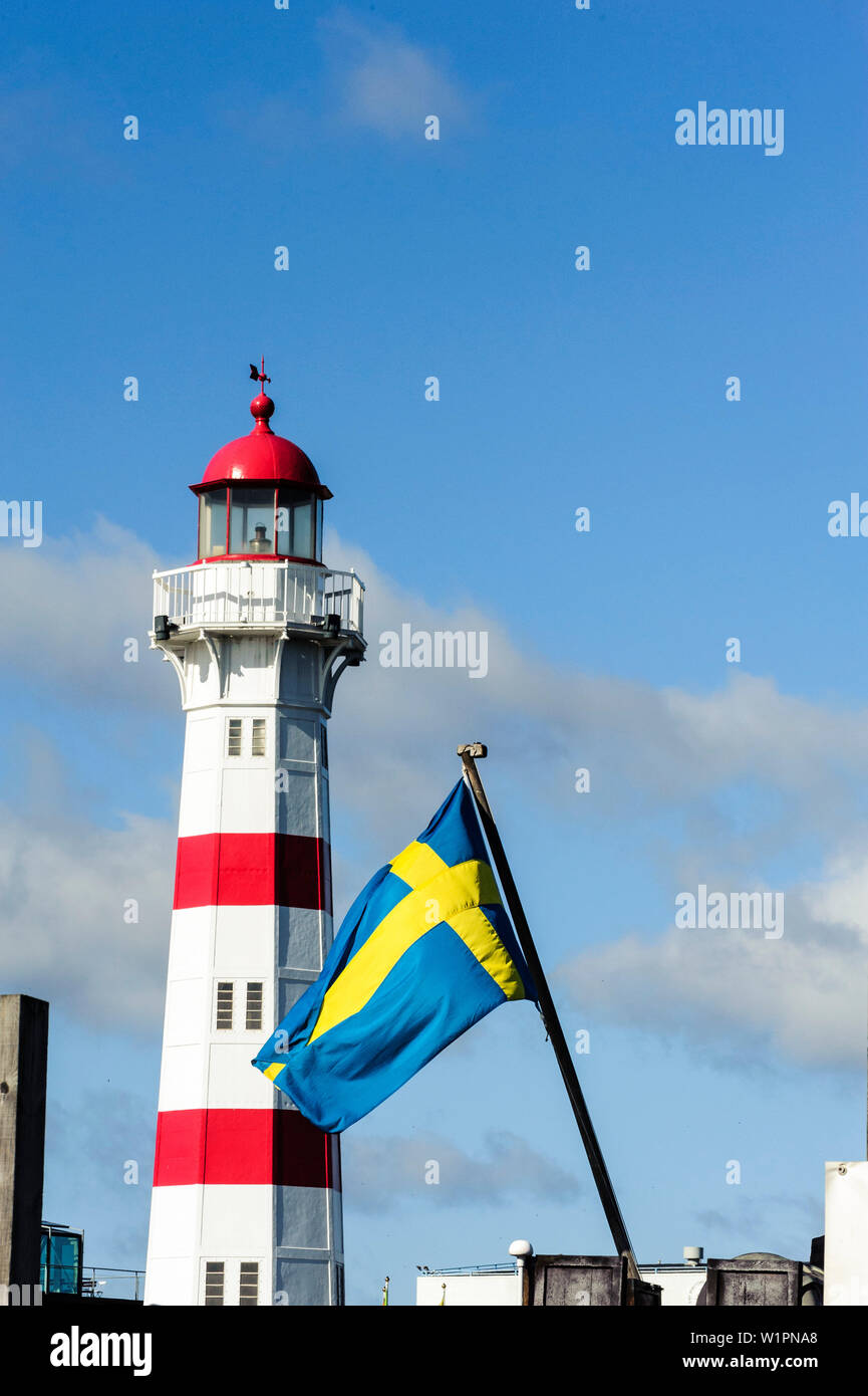 Red white lighthouse in sarnated harbor area with Swedish flag in front, Malmo, Southern Sweden, Sweden Stock Photo