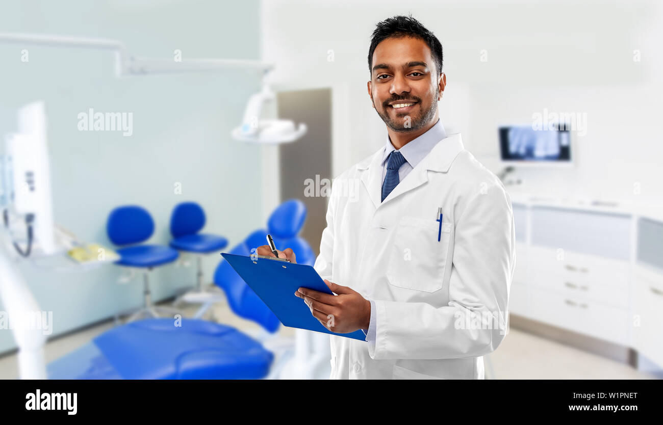 indian dentist with clipboard over dental clinic Stock Photo Alamy