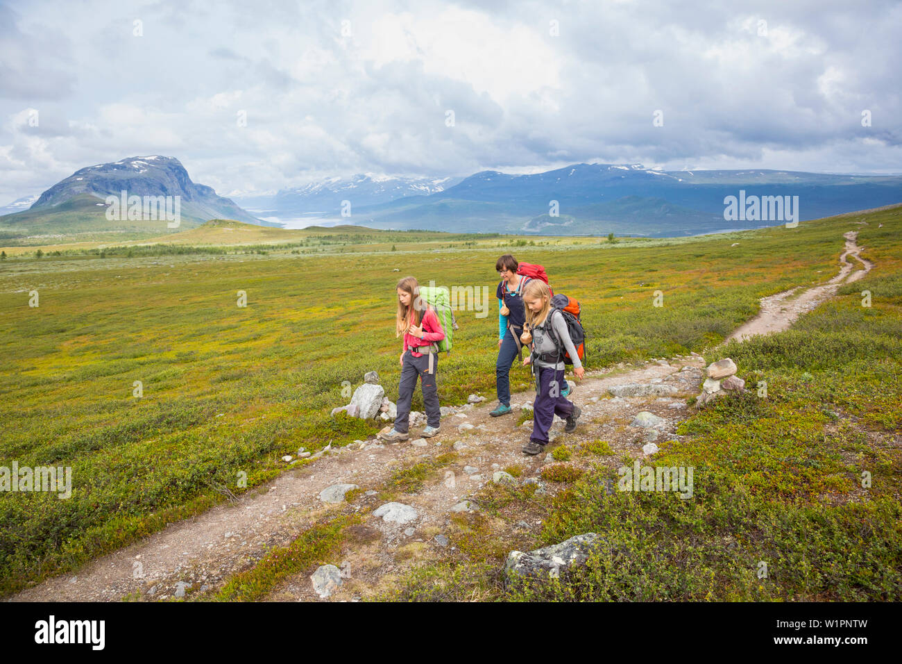 Two girls and one woman hike on the Kungsleden trekking, stage Saltoluokta to Sitojaurestugorna. Laponia, Lapland, Sweden. Stock Photo