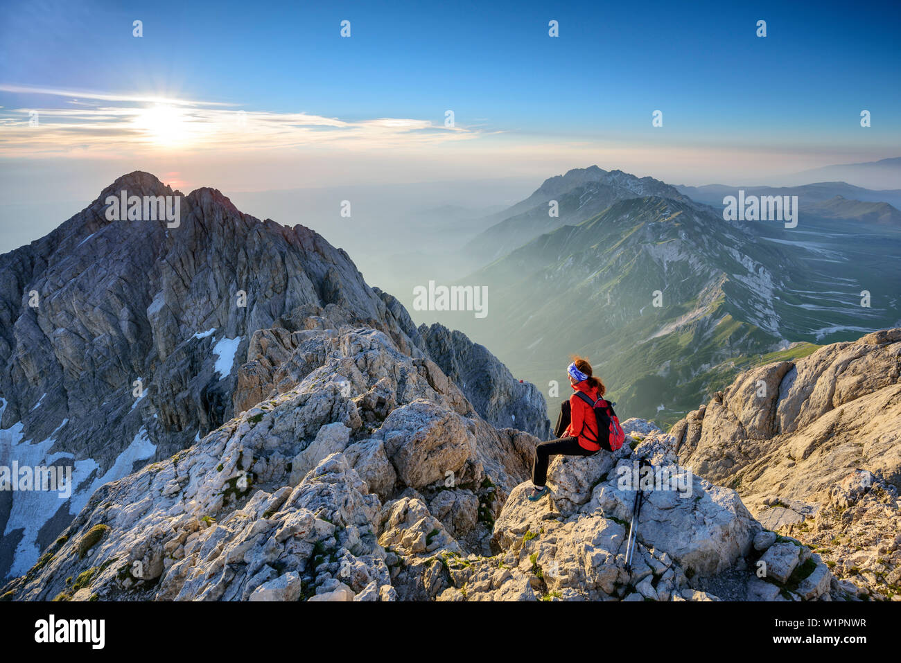 Woman hiking sitting at sunrise at Corno Grande, view to Gran Sasso-group, Corno Grande, Gran Sasso, Abruzzi, Italy Stock Photo