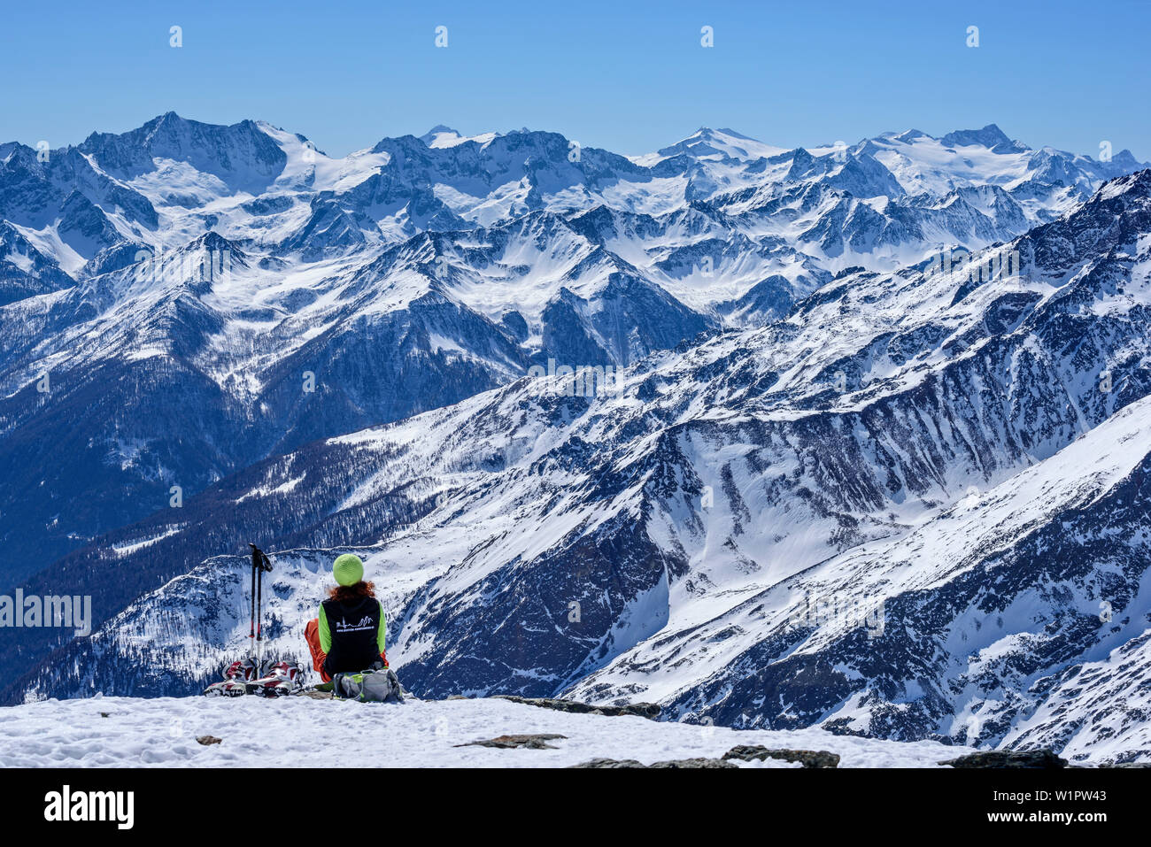 Woman backcountry skiing sitting at Cima Marmotta and looking towards Presanella and Adamello, Cima Marmotta, valley Martelltal, Ortler range, Vinschg Stock Photo