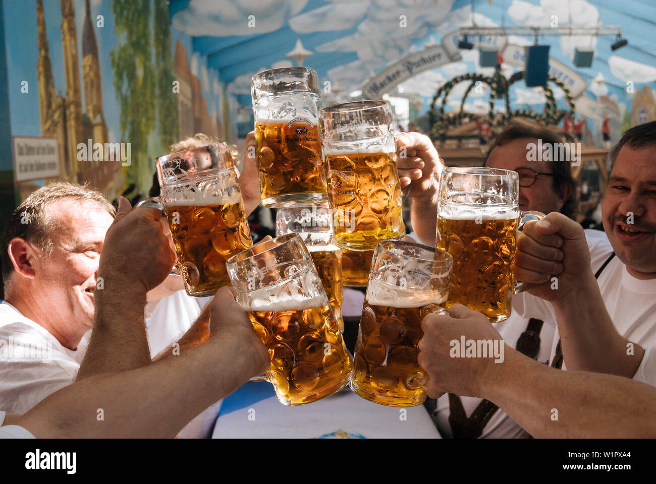 Raising beer mugs at Octoberfest, Munich, Bavaria, Germany Stock Photo