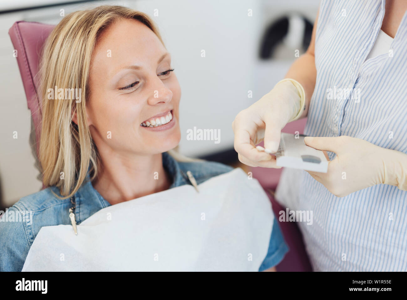 Dental nurse doing a color match on the enamel of the front teeth of a
