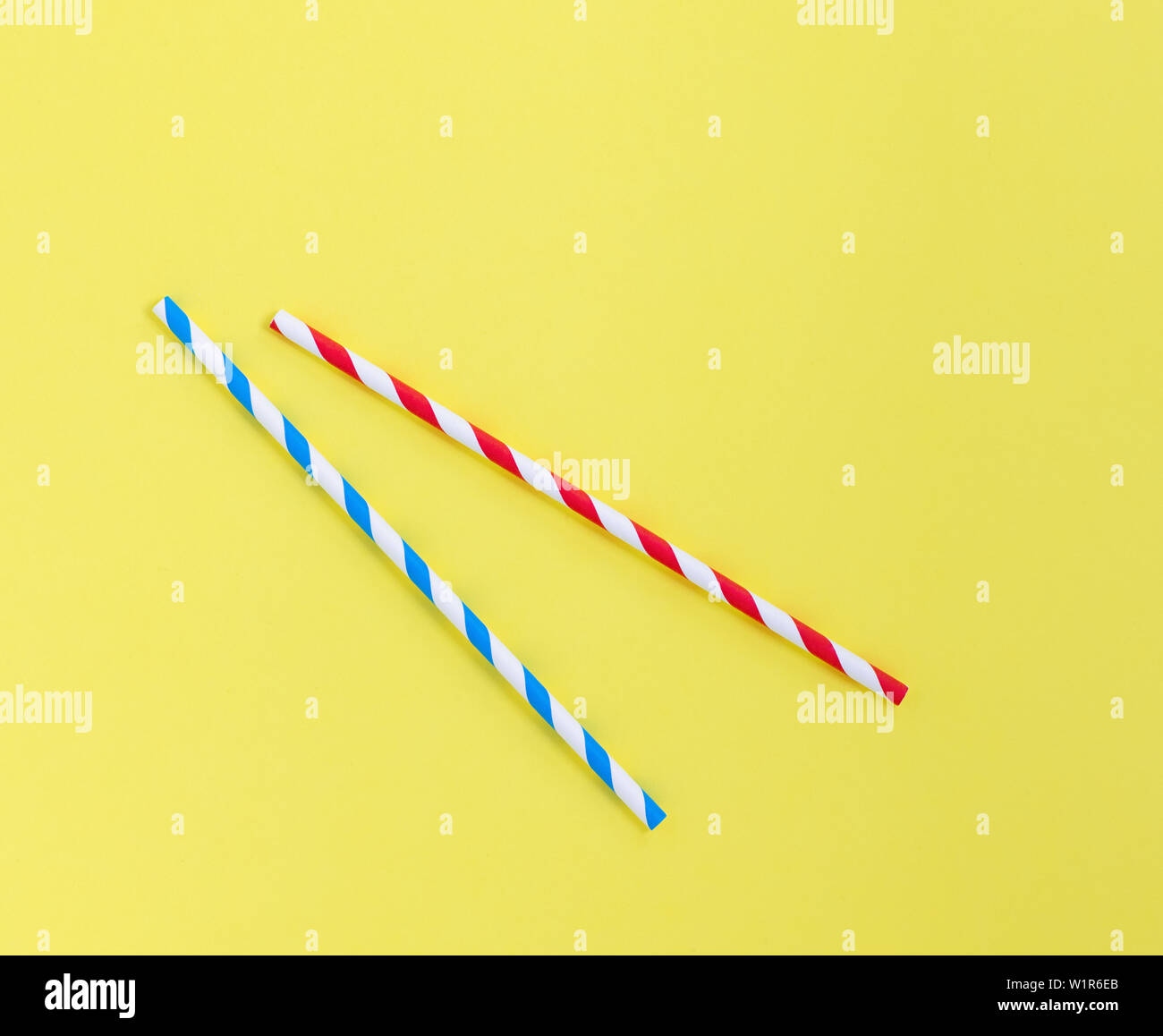 Paper straws on a yellow background. Blue and red stripes with copy space Stock Photo