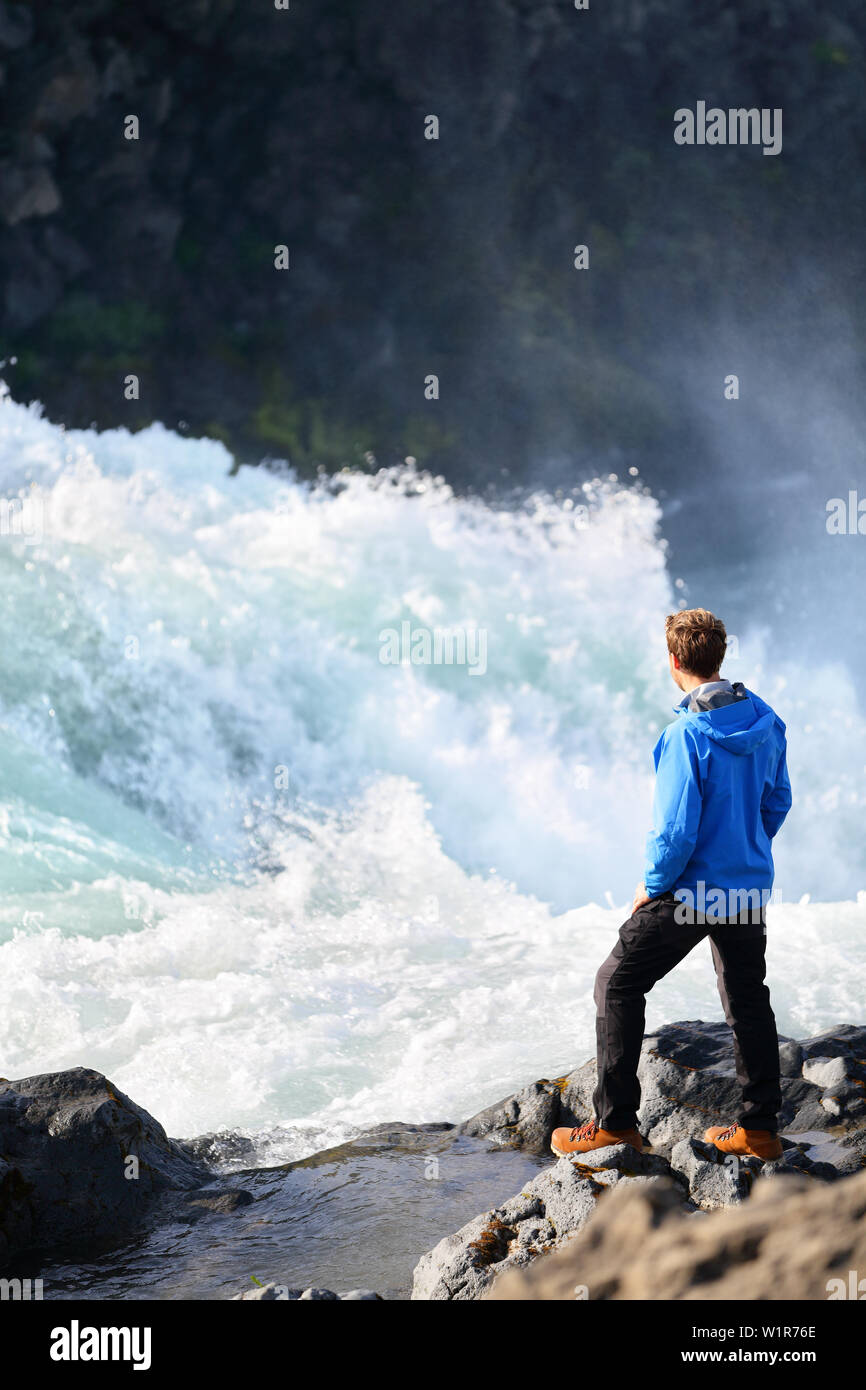 Iceland tourist looking at dramatic river by waterfall Godafoss. Man hiker on travel visiting tourist attractions and landmarks in Icelandic nature on Ring Road, Route 1. Stock Photo