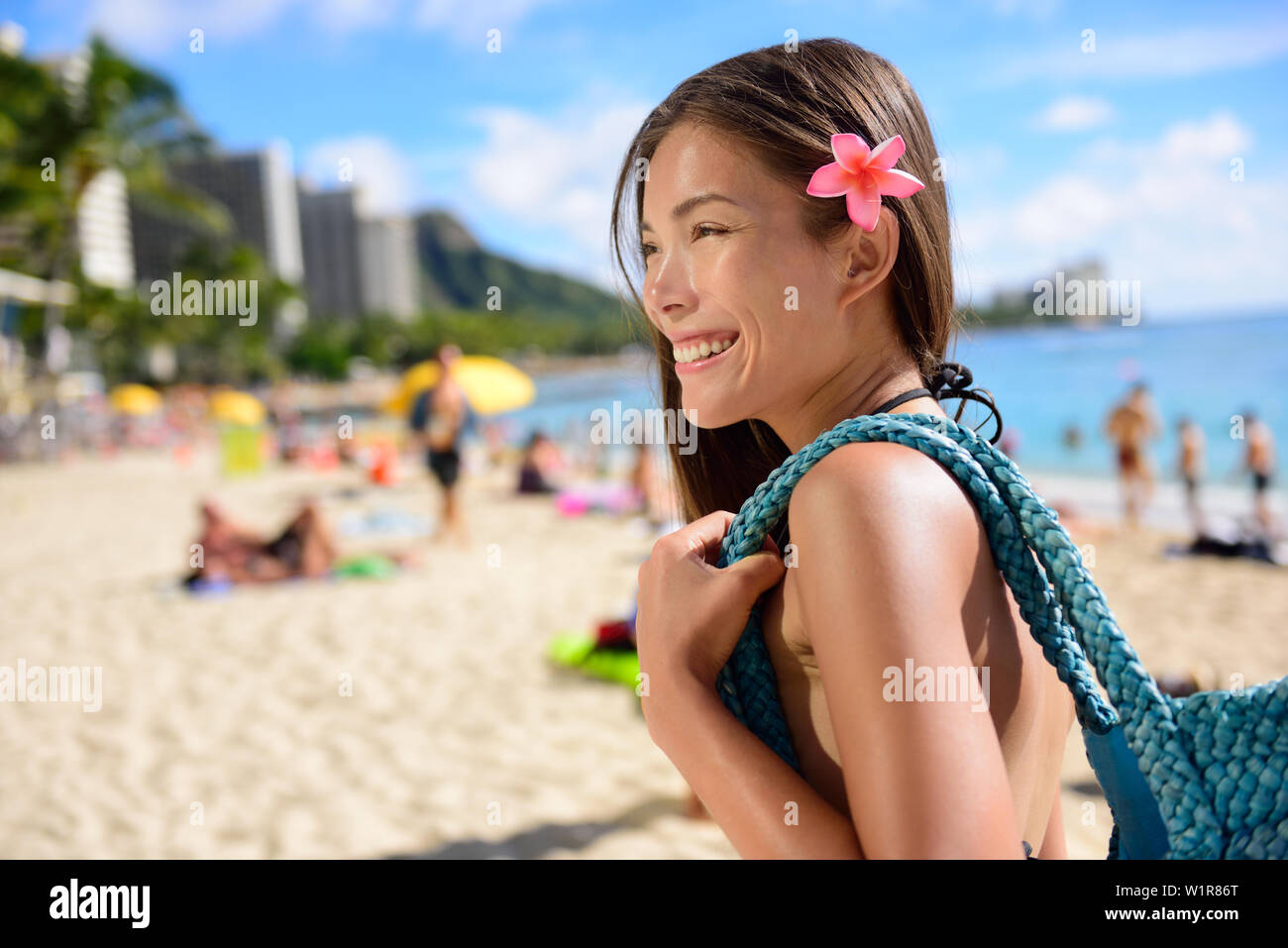 Asian tourist woman on vacation in Waikiki beach, Hawaii, USA. Pretty girl holding beach bag walking on famous touristic area in Honolulu city, Oahu, Hawaii, USA. Summer travel holiday concept. Stock Photo
