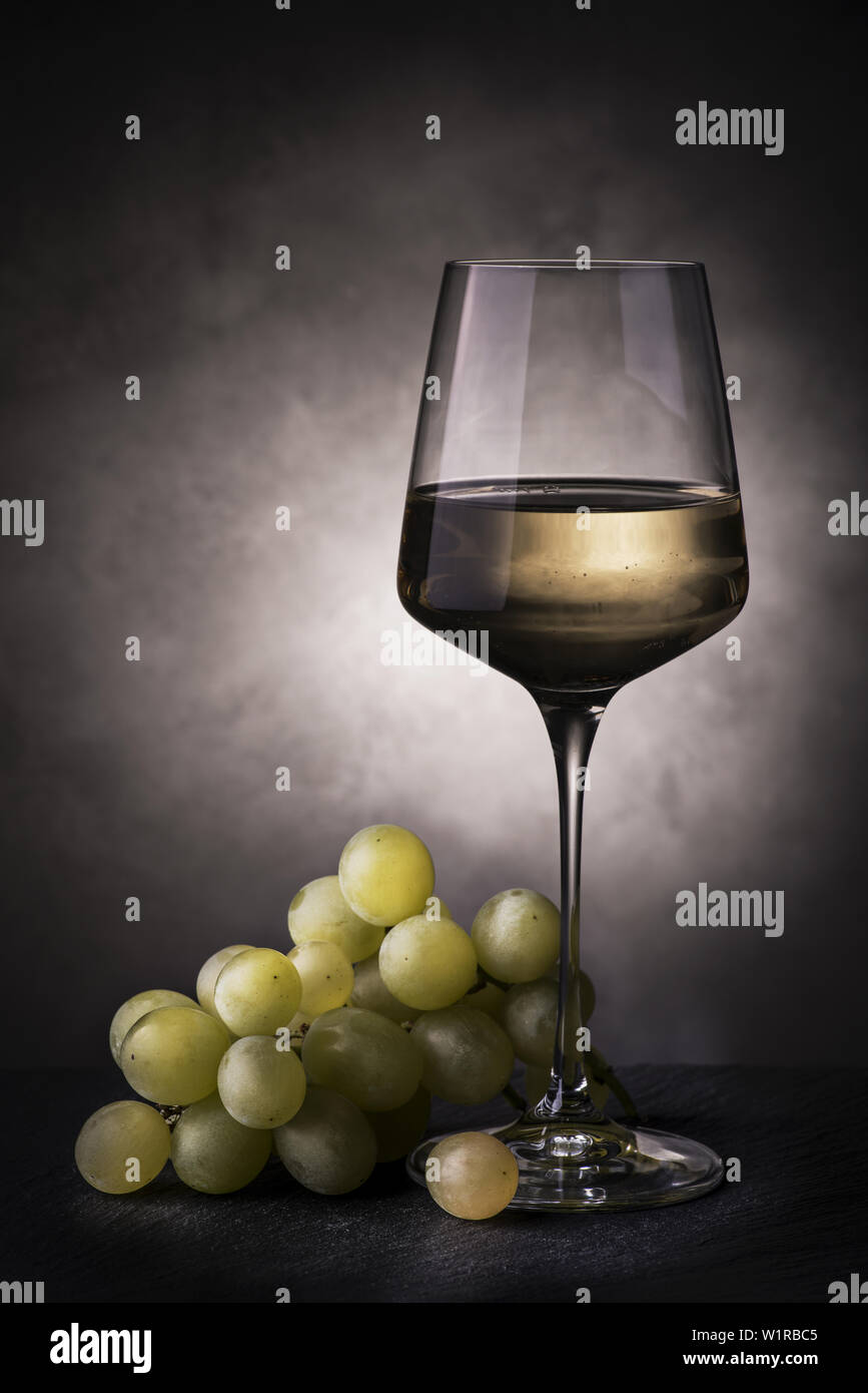 still life with glass of white wine and bunch of grapes Stock Photo