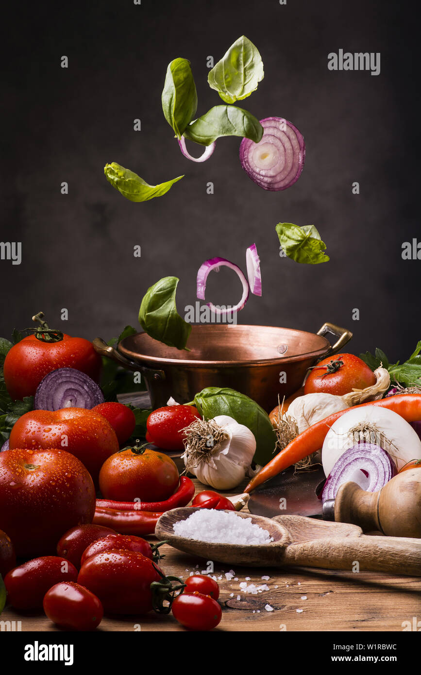 raw spices and vegetables on a wooden table ready for cooking in copper pot Stock Photo