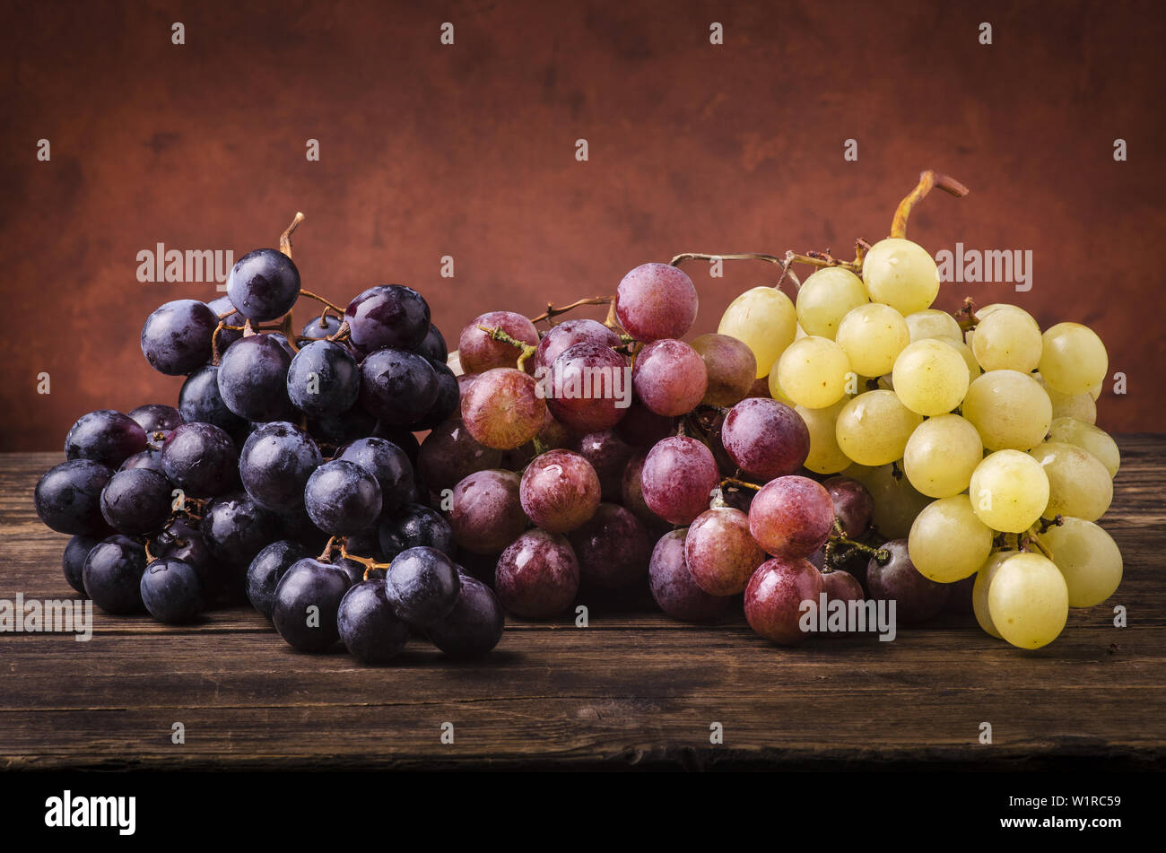 bunches of grapes of different types on a rough wooden table Stock Photo