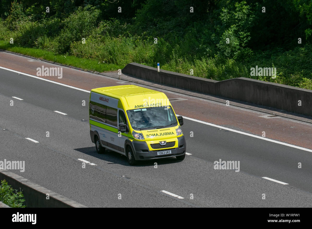 Yellow Private Ambulance Peugeot Boxer 435 L3H2 HDI; UK Vehicular traffic, Private Ambulance transport, modern, north-bound on the 3 lane M6 motorway highway. Stock Photo