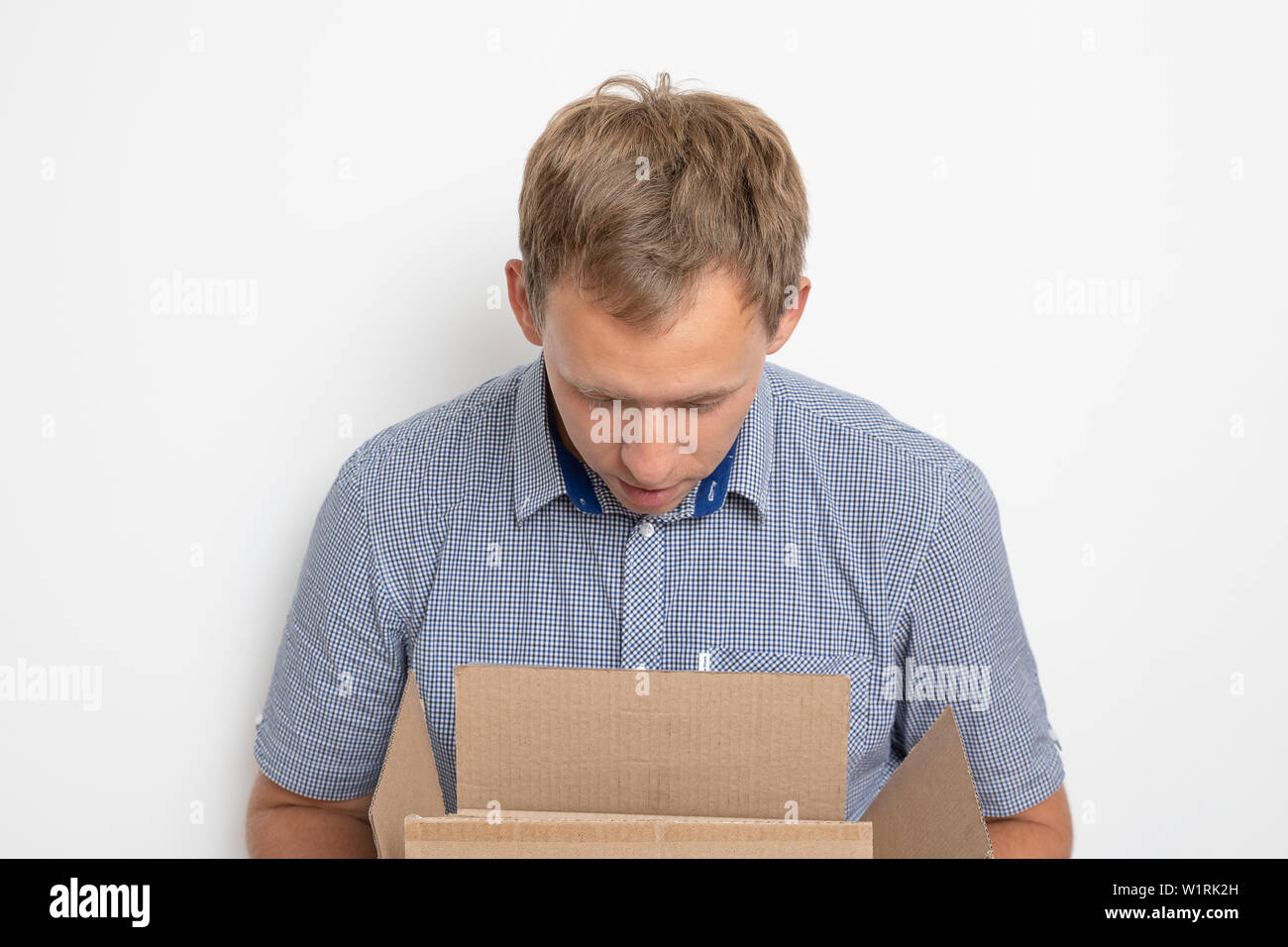 Description: curious man looking inside a cardboard box he holds in his hands on a white background Stock Photo