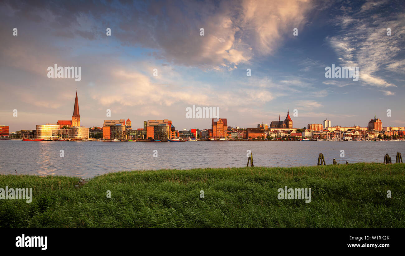 Rostock, Germany. Panoramic cityscape image of Rostock riverside with St. Peter's Church during summer sunset. Stock Photo