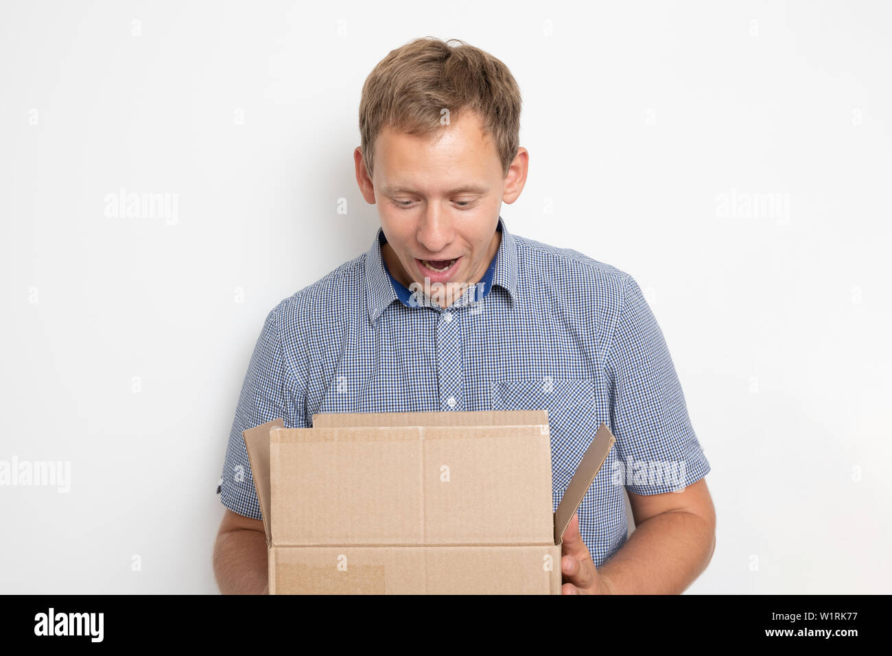 Description: curious man looking inside a cardboard box he holds in his hands on a white background Stock Photo