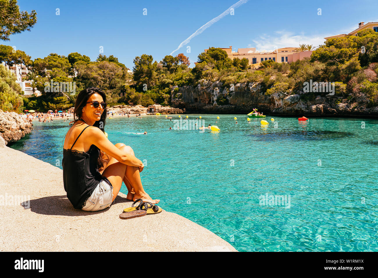 Woman enjoying the view of turquoise water in Cala Ferrera in a sunny day, Cala D'Or, Majorca. Stock Photo
