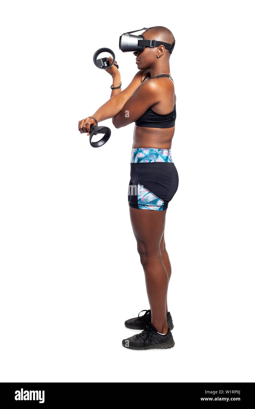 Black female wearing a virtual reality headset and holding wand controllers doing vr fitness exercises