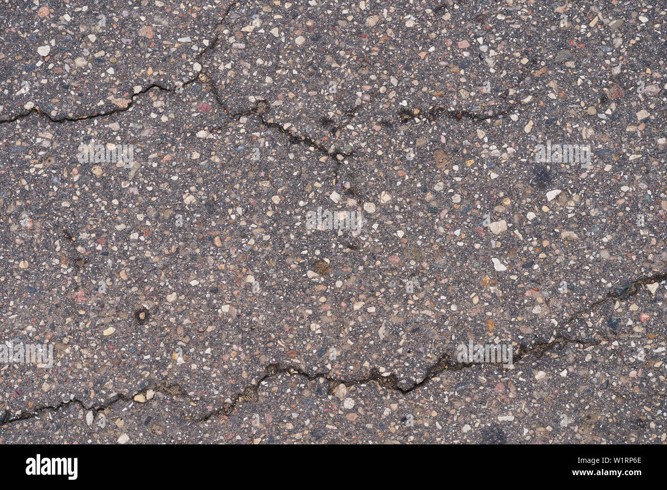 Asphalt road surface with small cracks and damages. Stock Photo