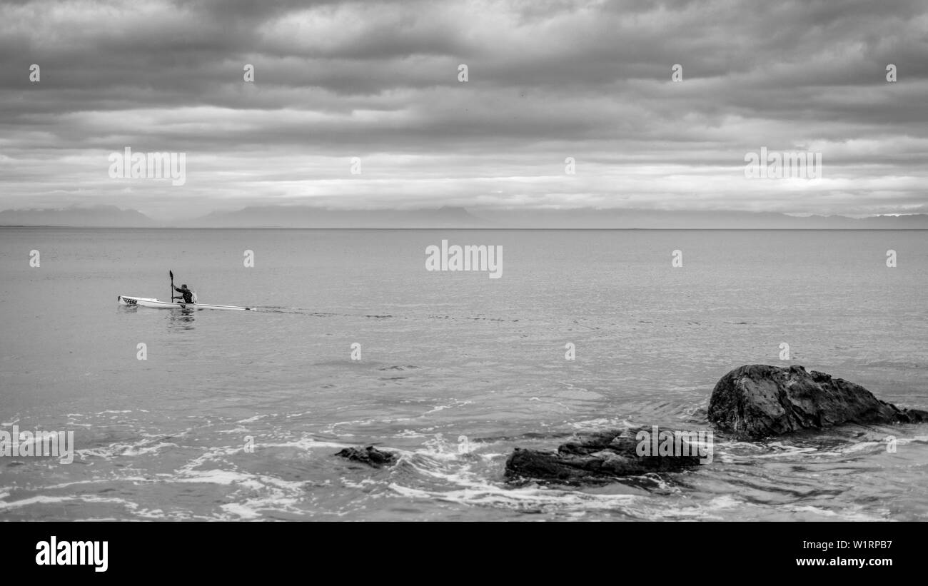 A canoeist paddles along the False Bay coastline during the winter months near Cape Town in South Africa Stock Photo