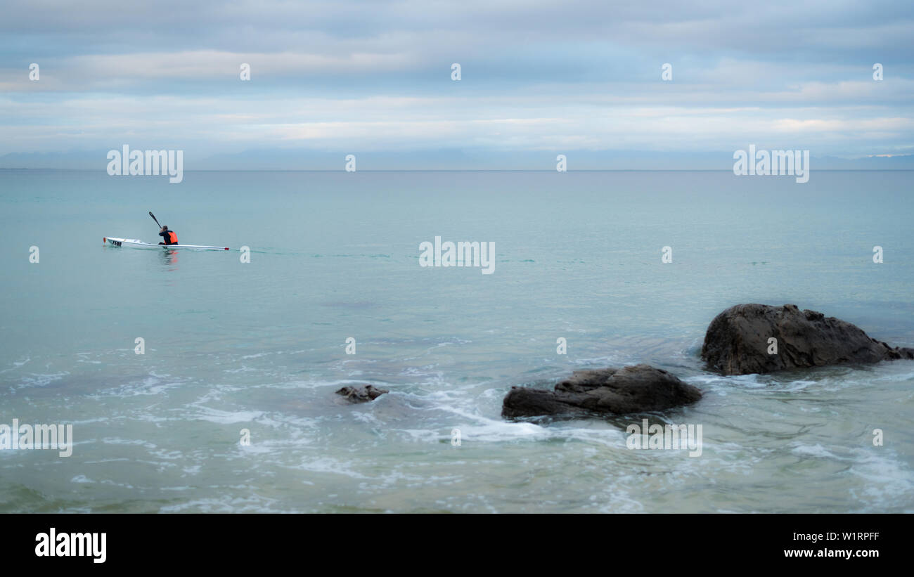 A canoeist paddles along the False Bay coastline during the winter months near Cape Town in South Africa Stock Photo