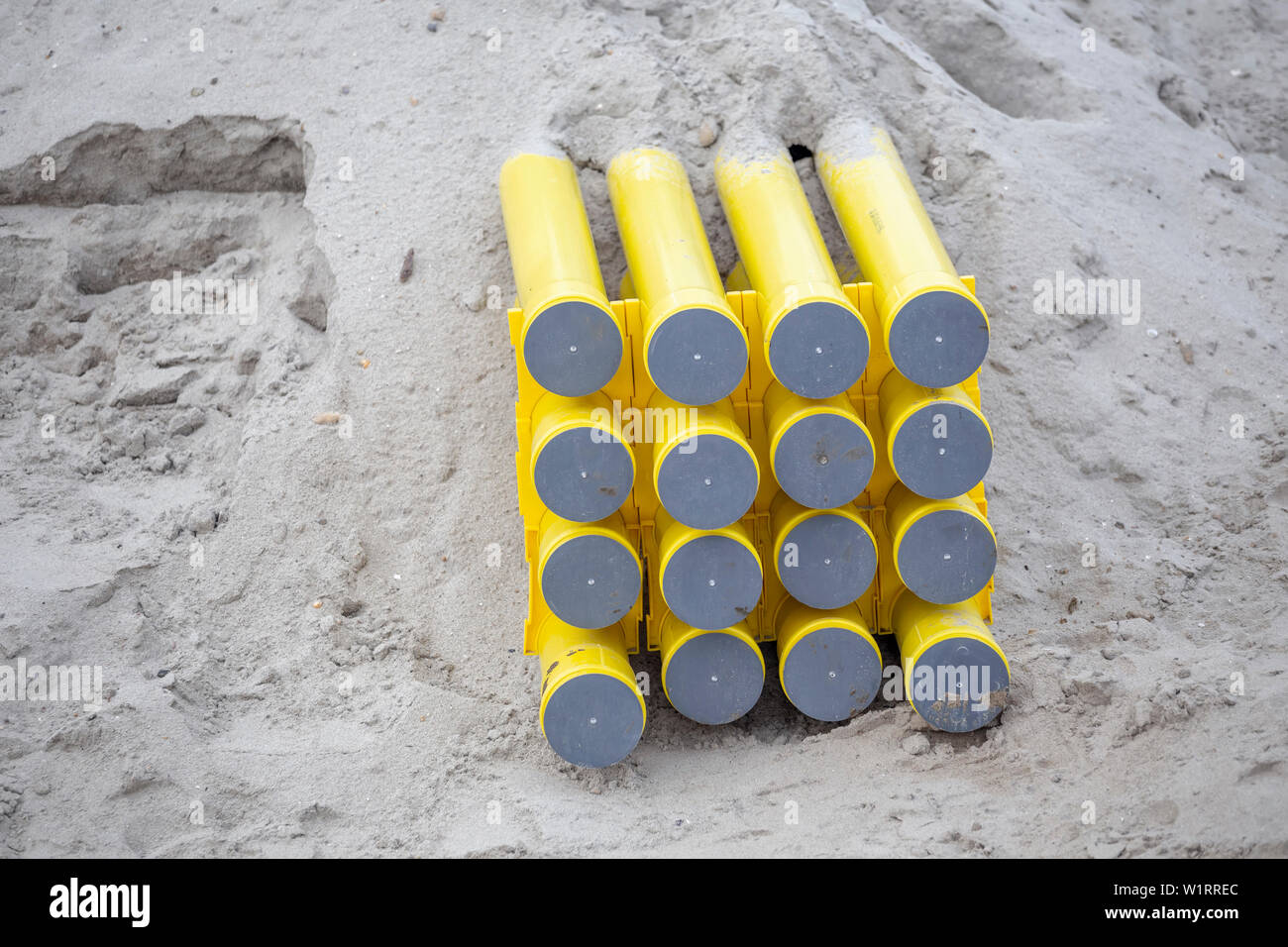 Yellow PVC pipes for cable systems buried in the sand. Polyethylene