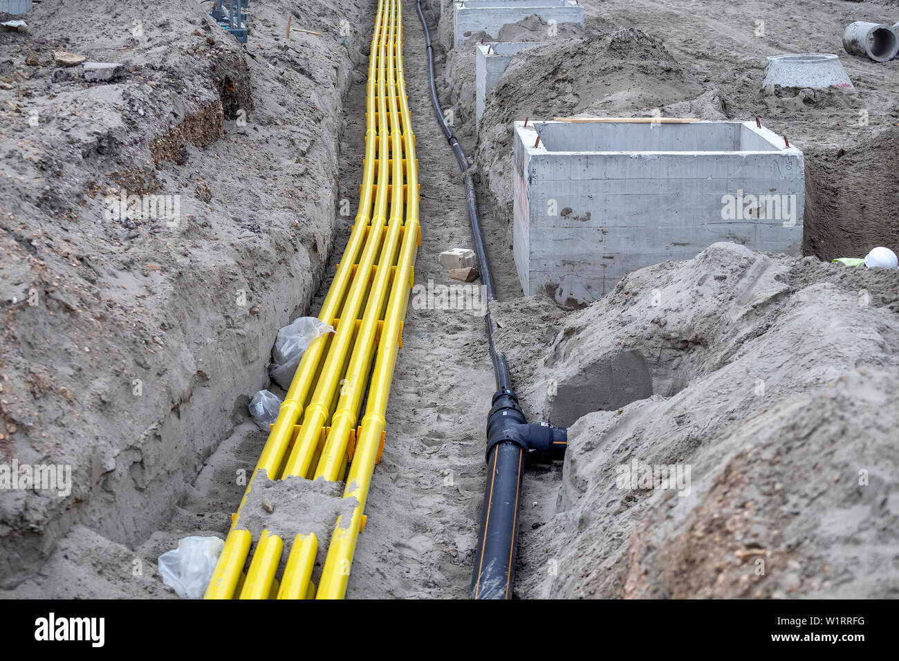 Yellow PVC pipeline for cable systems buried in the sand. Polyethylene pipes are used as channels for optical cables and providing protection for tele Stock Photo