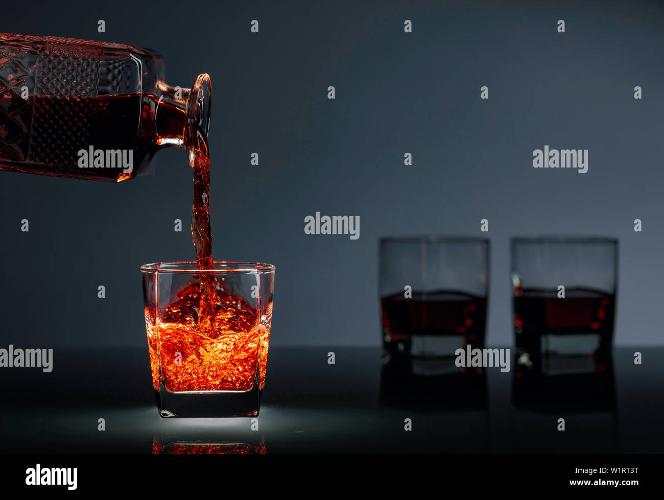 Pouring whiskey or scotch  into glass. Alcoholic drink pouring from a decanter into a glass. Copy space. Stock Photo