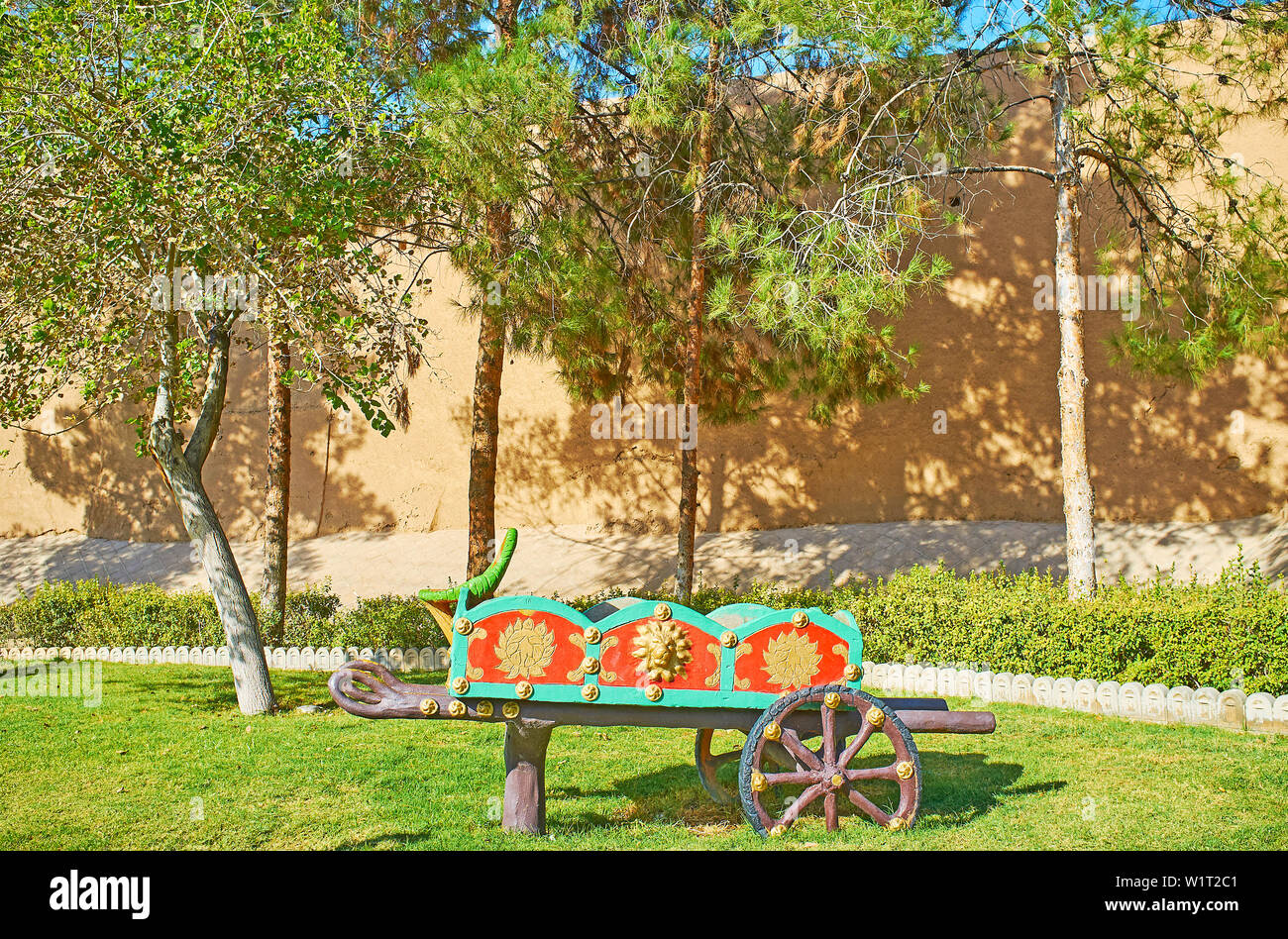 Watch the garden sculpture of old cart in green Mellat park, stretching along Ghal'eh Jalali fortress wall, Kashan, Iran Stock Photo