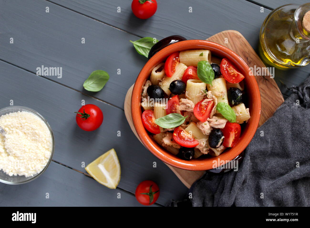 Pasta with tuna, tomato, black olive and parmesan cheese on dark background. Top view with copy space. Stock Photo