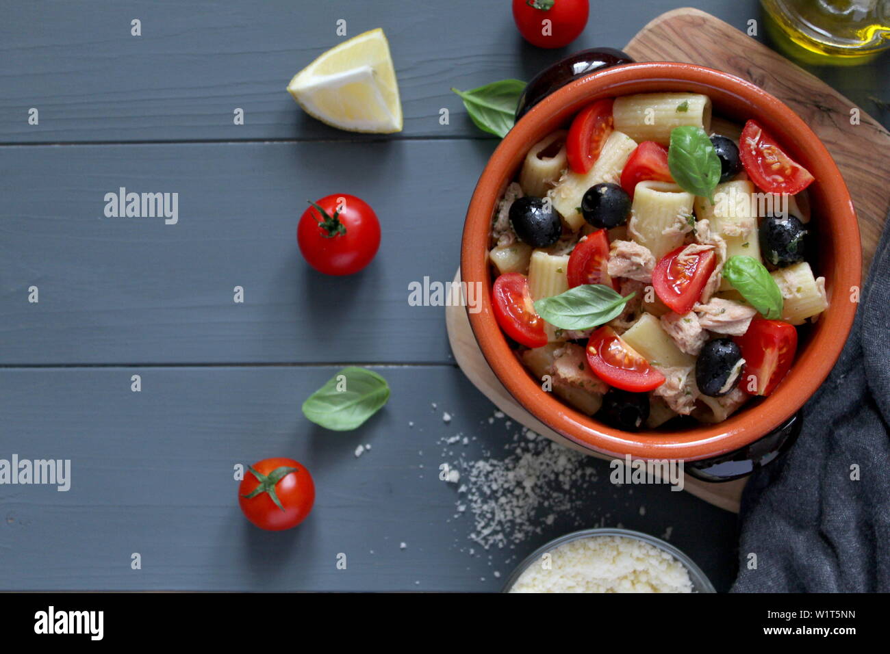 Pasta with tuna, tomato, black olive and parmesan cheese on dark background. Top view with copy space. Stock Photo
