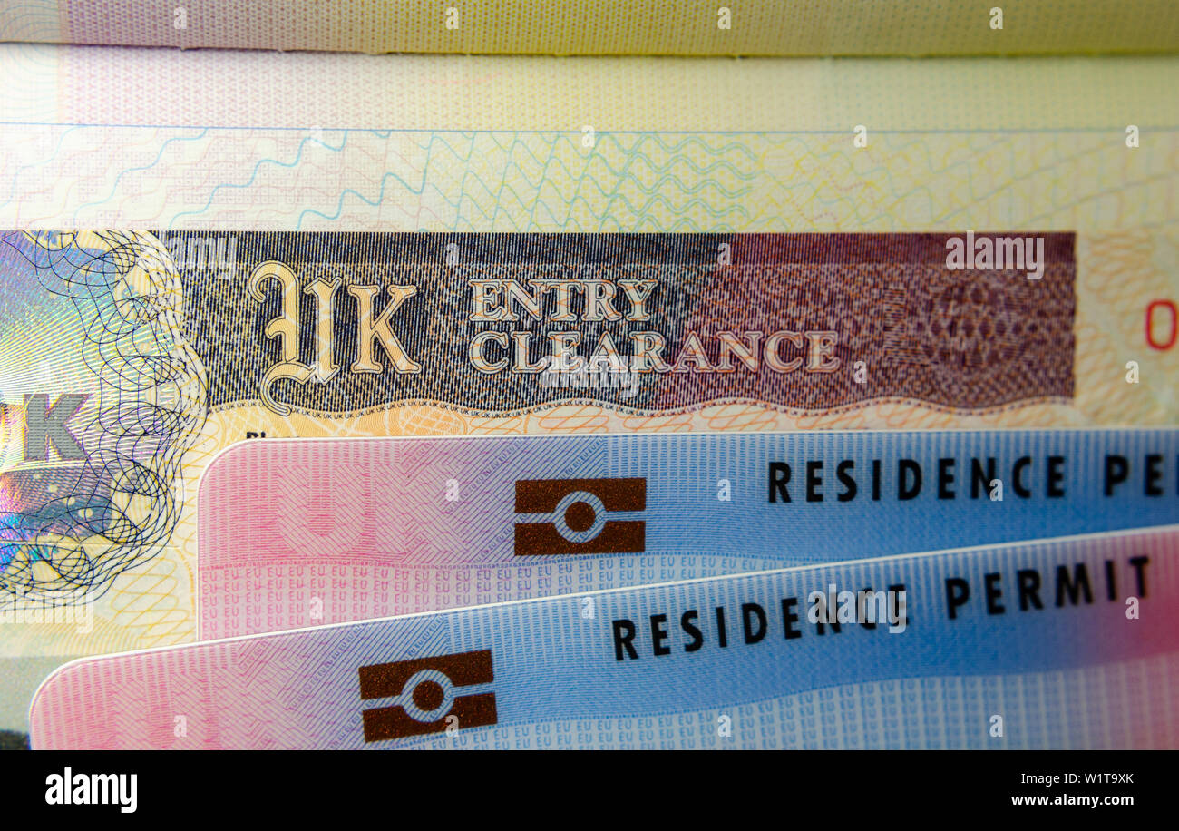 UK BRP (Biometrical Residence Permit) cards for Tier 2 work visa placed on top of UK Entry Clearance vignette sticker in the passport. Stock Photo