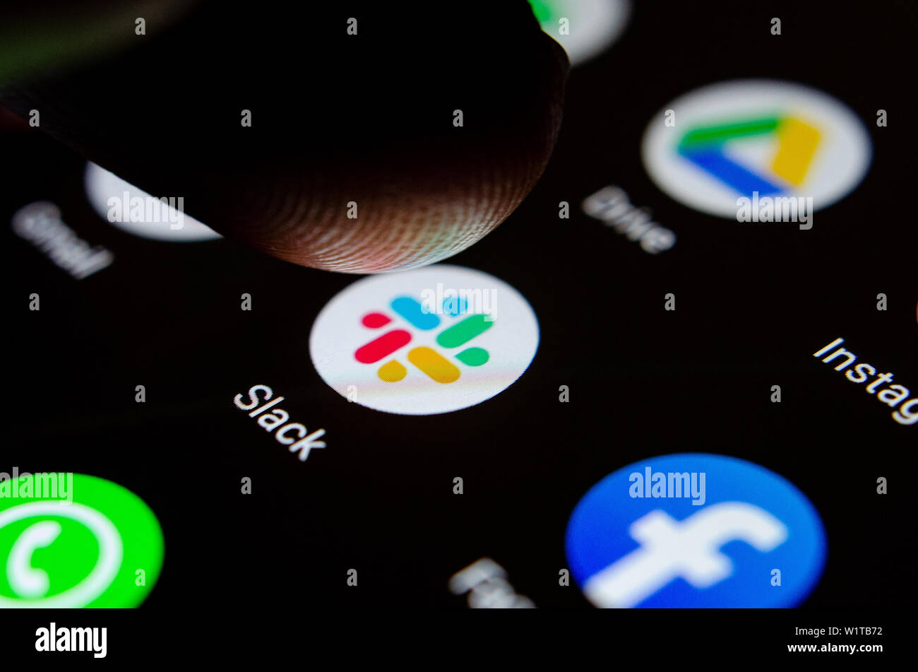 Close up photo Slack app on the smartphone screen and a finger launching it. The top app for communication and collaboration. Stock Photo