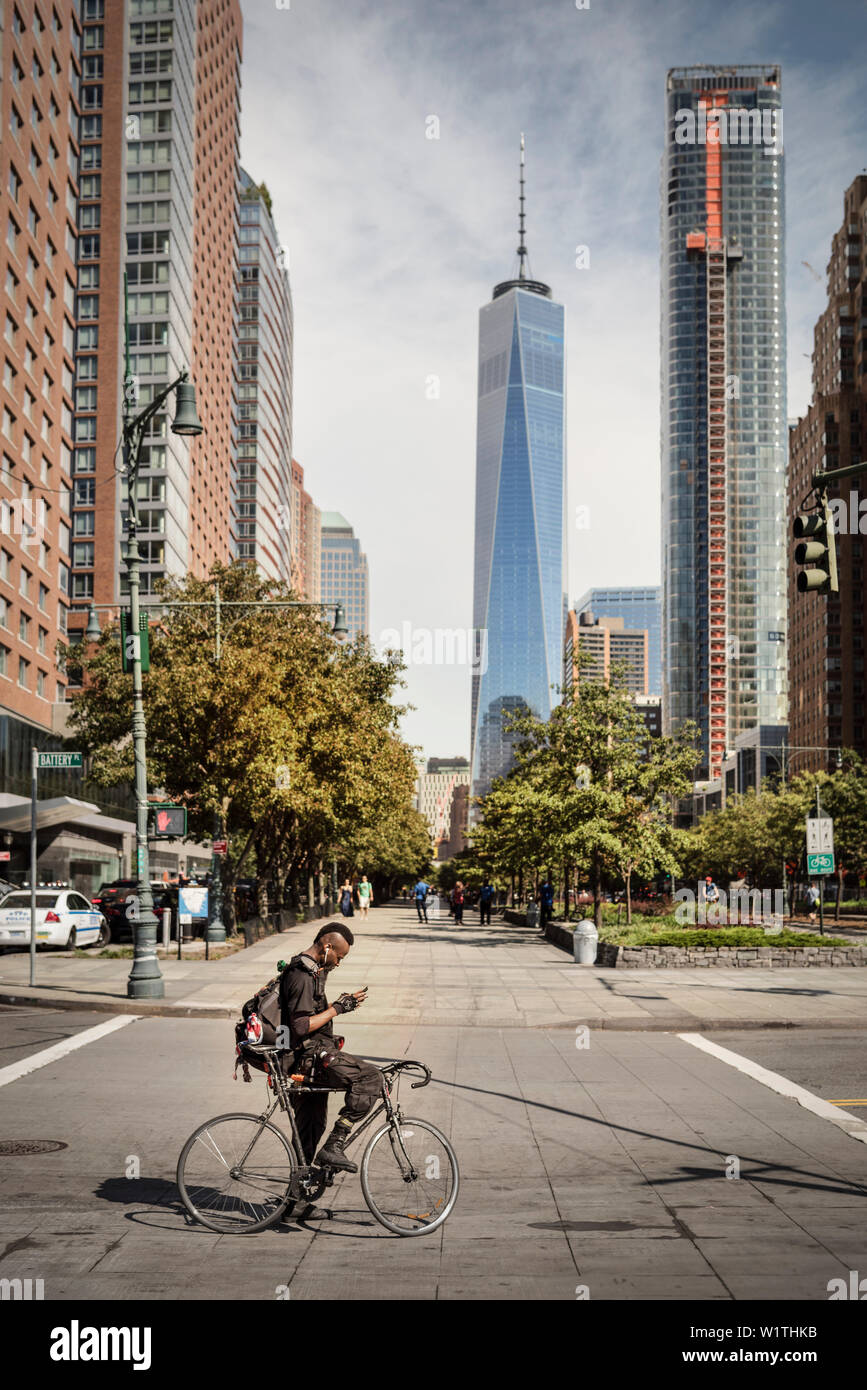 stylish New Yorker with Iroquois sitting on a racing bike in front of ONE World Trade Center and looking at mobile phone, Manhattan, NYC, New York Cit Stock Photo