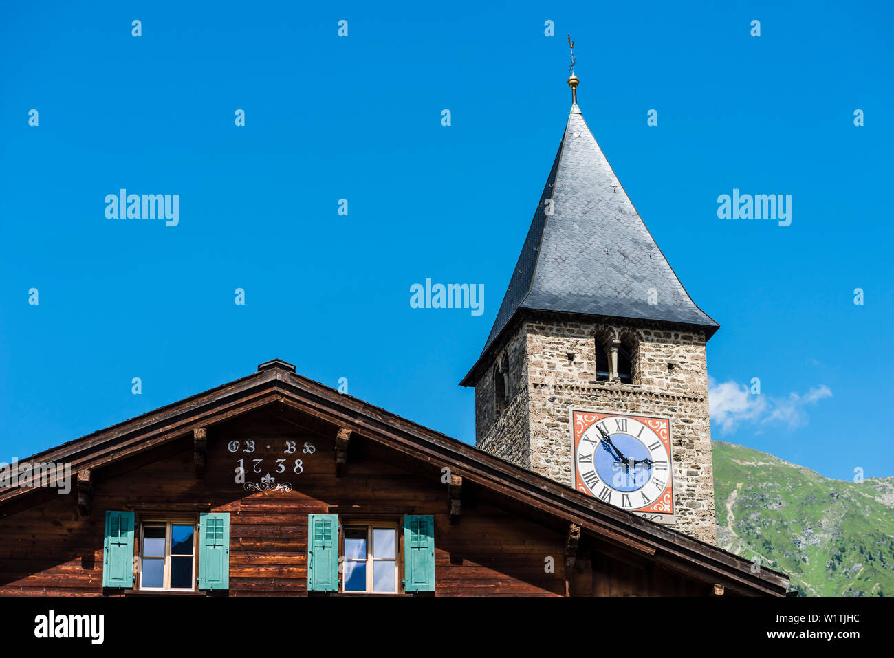 An old timber house and the church in the village center, Saas im Praettigau, Klosters, Grisons, Switzerland Stock Photo